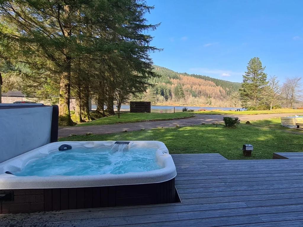 a hot tub on a deck with a view of a park at Bonnie Lodge-Lochside Location with Hot Tub in Invergarry
