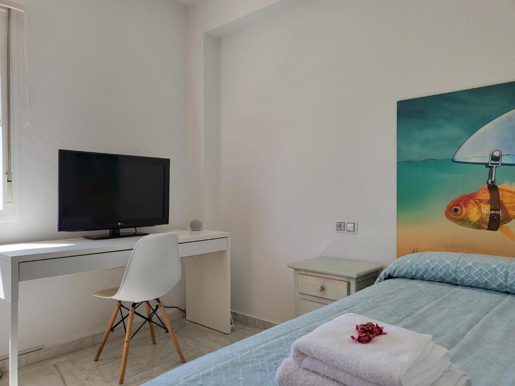 a bedroom with a bed and a desk with a television at Adosado de lujo en El Portil Playa y Golf in El Portil