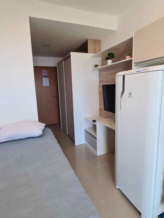 a small room with a refrigerator and a bed at Lindo Studio frente Mar Matinhos/PR. in Matinhos