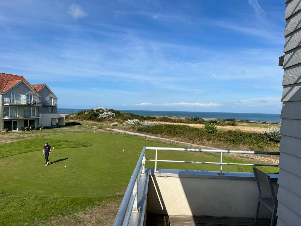 un hombre jugando al golf en un verde con el océano en Vue sur mer XXL, en Wimereux