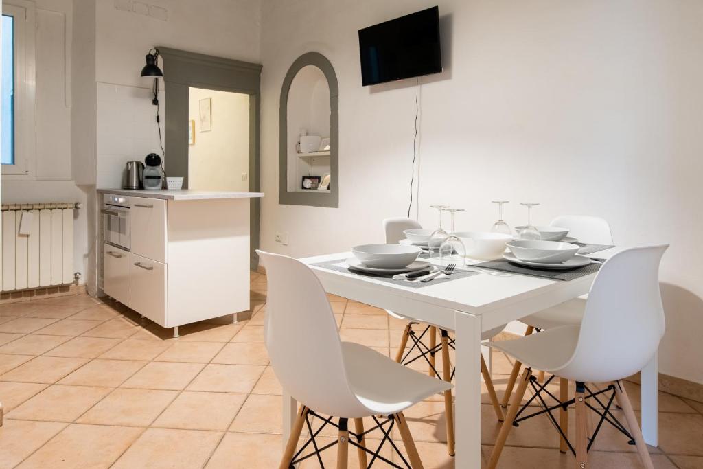 un comedor blanco con una mesa y sillas blancas en 2 Rooms next to a market and Piazza Santa Croce - HomeUnity, en Florencia