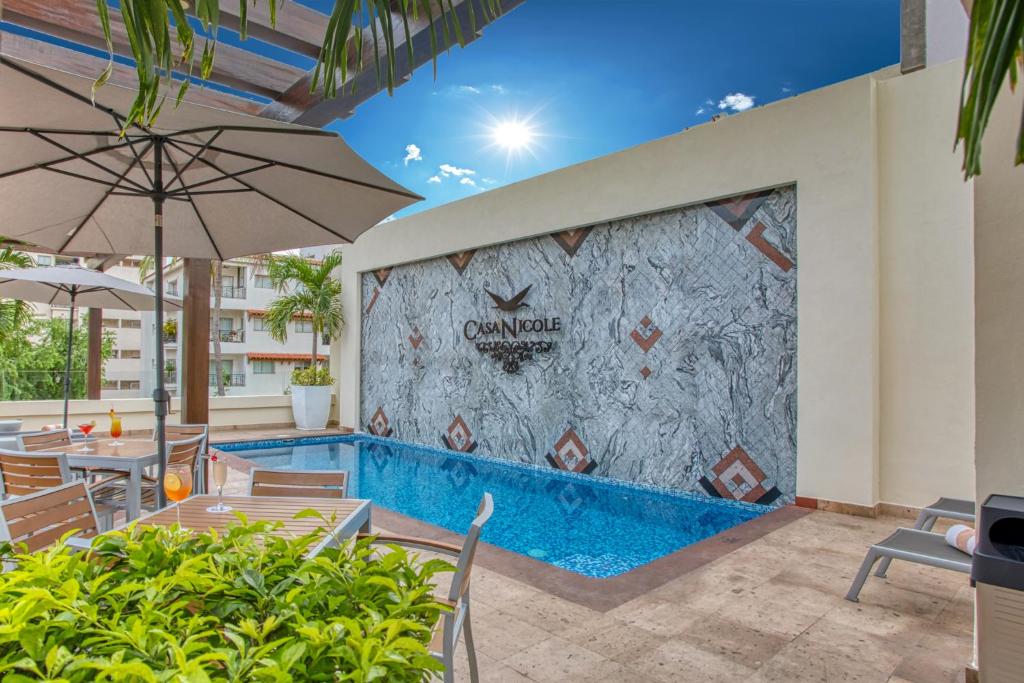 uma piscina num hotel com cadeiras e um guarda-sol em Casa Nicole Boutique Hotel em Puerto Vallarta