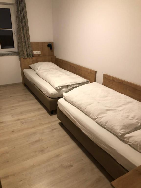 Duas camas num pequeno quarto com pisos em madeira em Pension Beil em Sauerlach
