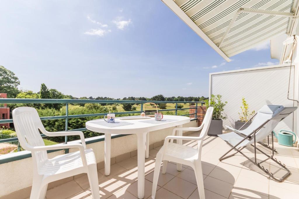 d'une terrasse avec une table et des chaises blanches sur un balcon. dans l'établissement La Terrasse du golf, à Pornic