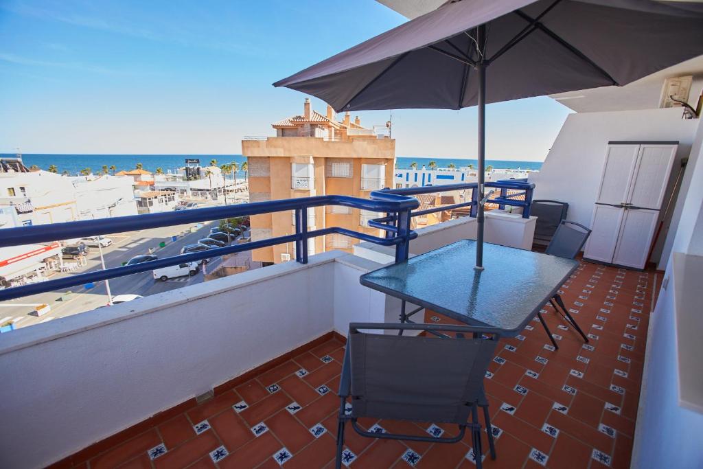 a balcony with a table and an umbrella at VistAzul 401 in La Antilla