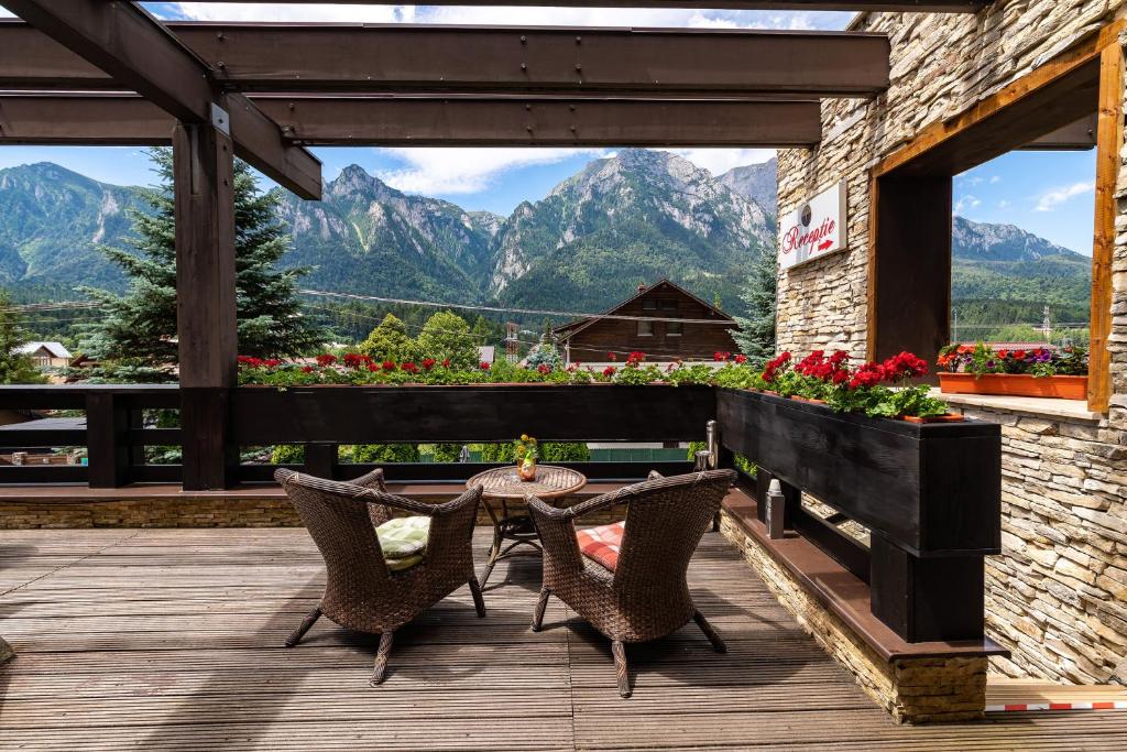 a patio with a table and chairs and mountains at Casa Freya in Buşteni