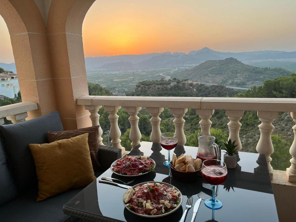 una mesa con dos platos de comida y copas de vino en VILLA CASA JOLI in Oliva with private pool and stunning views, en Oliva