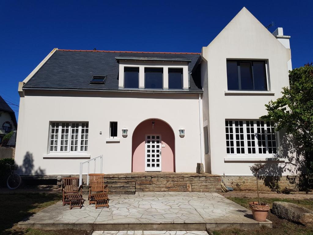 une maison blanche avec des chaises devant elle dans l'établissement Villa sur la corniche vue mer, à Concarneau