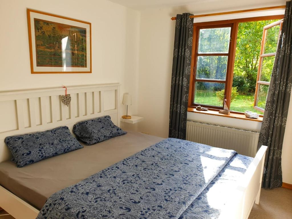a bedroom with a bed with a blue comforter and two windows at Ferienwohnung Hyggebo in Langballig