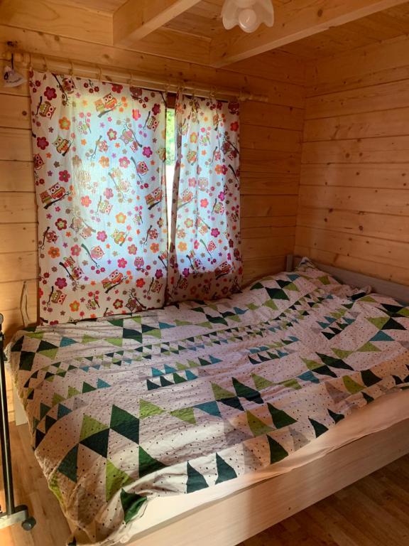 ein Bett in einer Hütte mit einer Decke darauf in der Unterkunft Domki u Wiesi in Giżycko