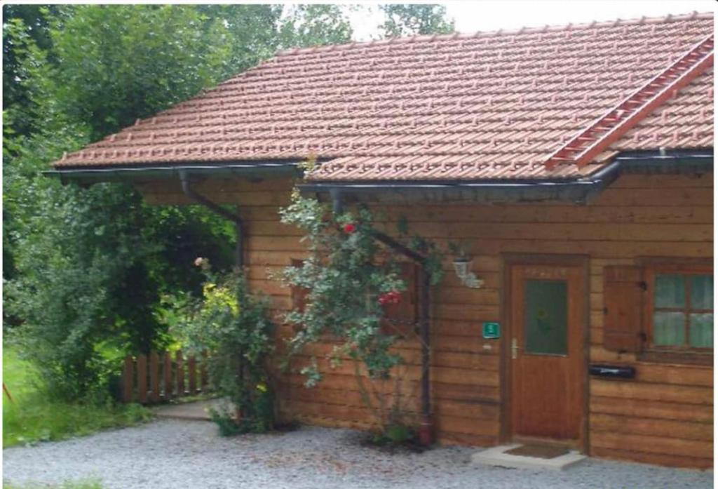 una pequeña casa de ladrillo con techo rojo en Ferienhaus Schlagintweit, en Drachselsried