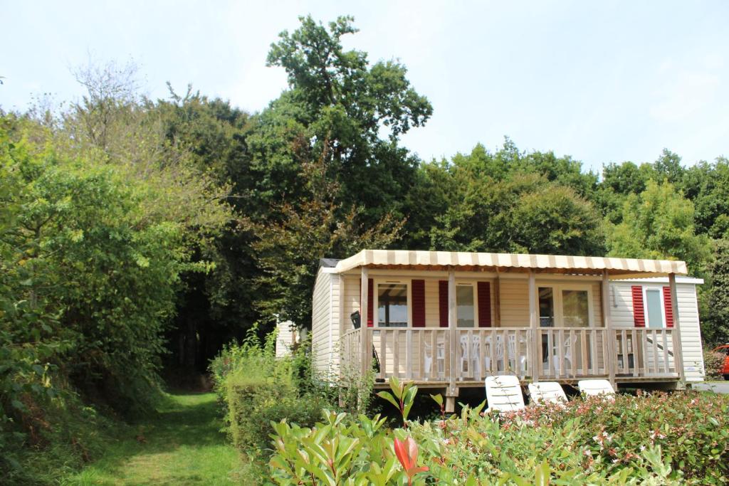 La nature en famille في Litteau: منزل صغير مع شرفة وكراسي في حديقة