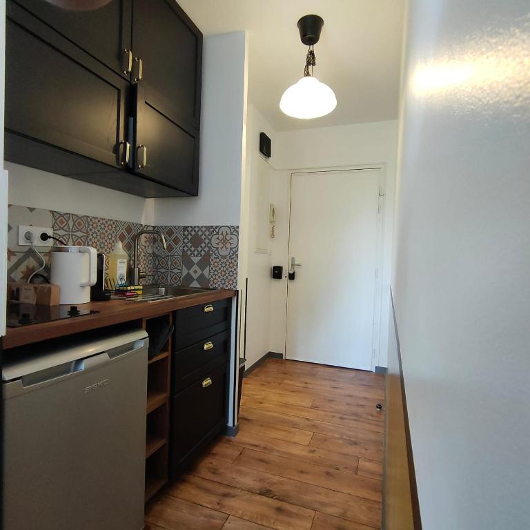 une cuisine avec des armoires noires et un plancher en bois dans l'établissement Studio Emotion 4P - Train station 200m - Disneyland Paris 5 min, à Montévrain