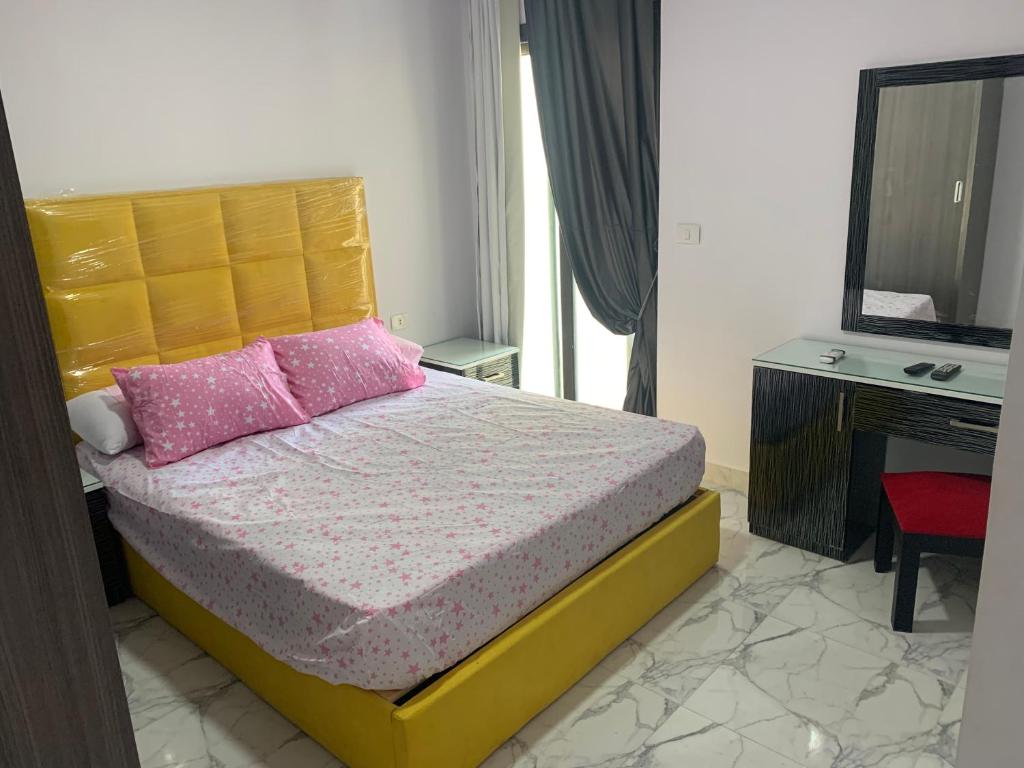 een slaapkamer met een bed met roze kussens en een televisie bij بورتو سعيد Portosaid in Port Said