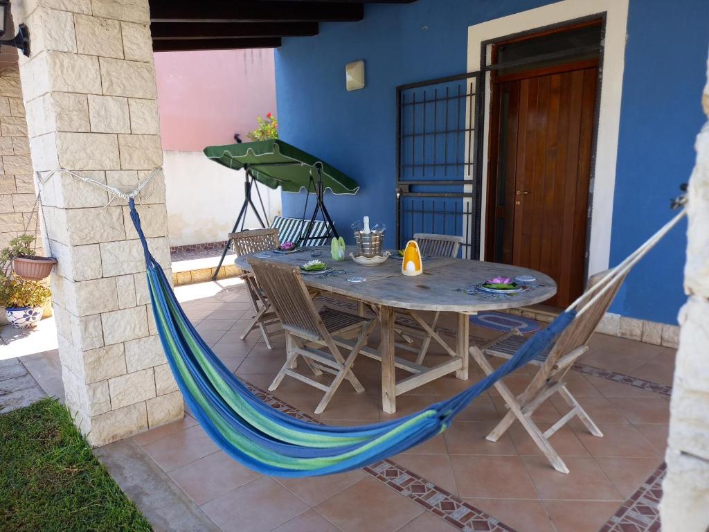 - une table avec des chaises et un hamac sur la terrasse dans l'établissement Villa Serena, à Granelli