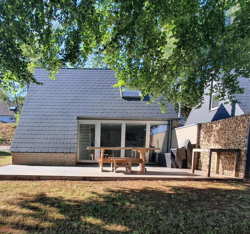 un patio con un banco y una mesa frente a una casa en Aux 4 vents - Malmedy en Malmedy