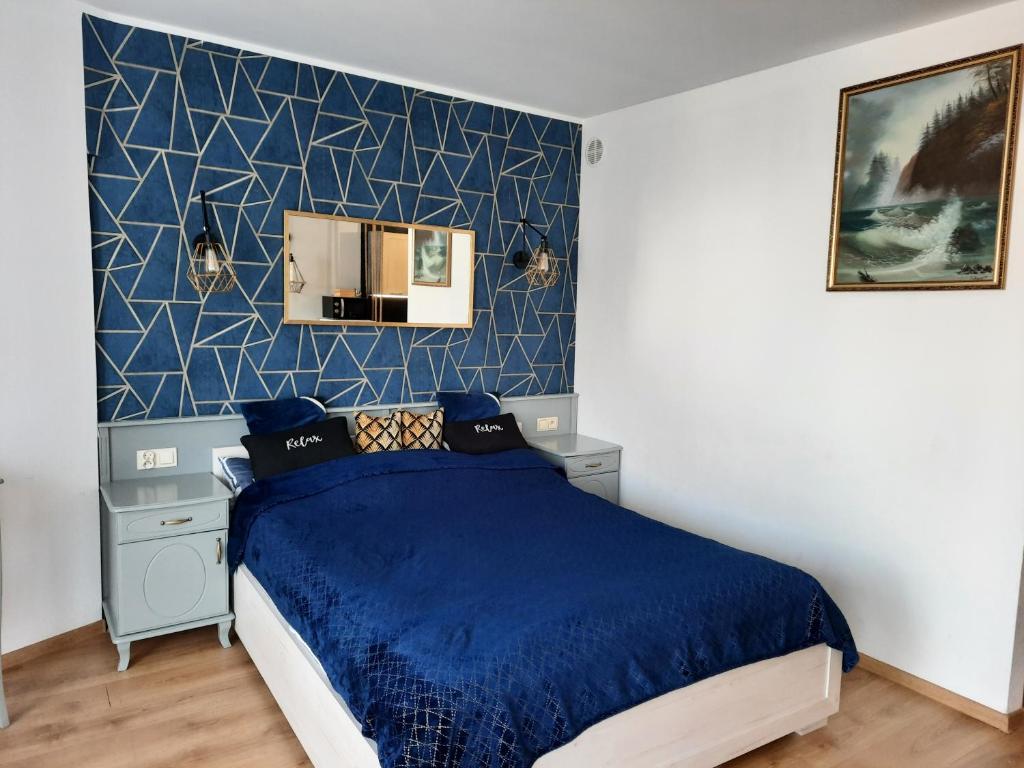 una camera con letto e parete blu di Apartament w Kołobrzegu blisko plaży, parku i promenady a Kołobrzeg