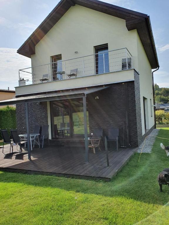 a house with a wooden deck with chairs on it at Vila pod Černou horou in Rožnov pod Radhoštěm