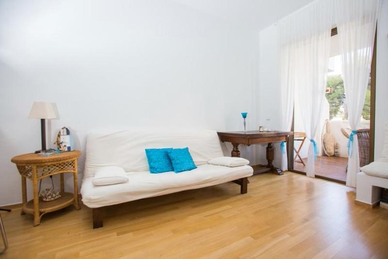 un sofá blanco con almohadas azules en la sala de estar. en Άνετη διαμονή 100 μέτρα από τη θάλασσα - Βάρκιζα, en Vari
