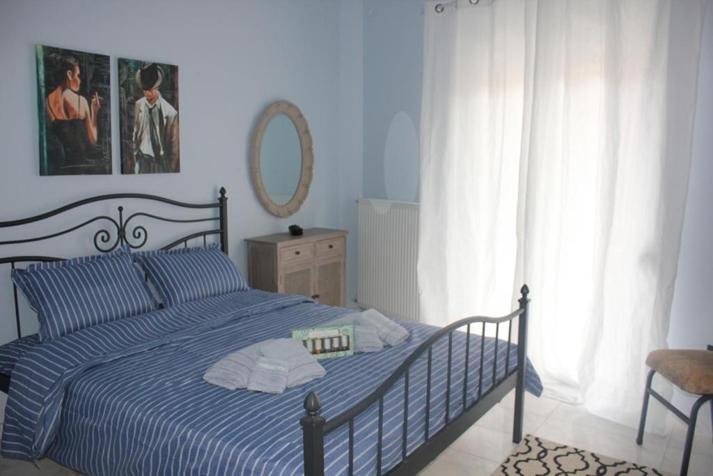 een slaapkamer met een bed met een blauw gestreept dekbed en een spiegel bij Modern house next to Metro station to explore Athens in Athene