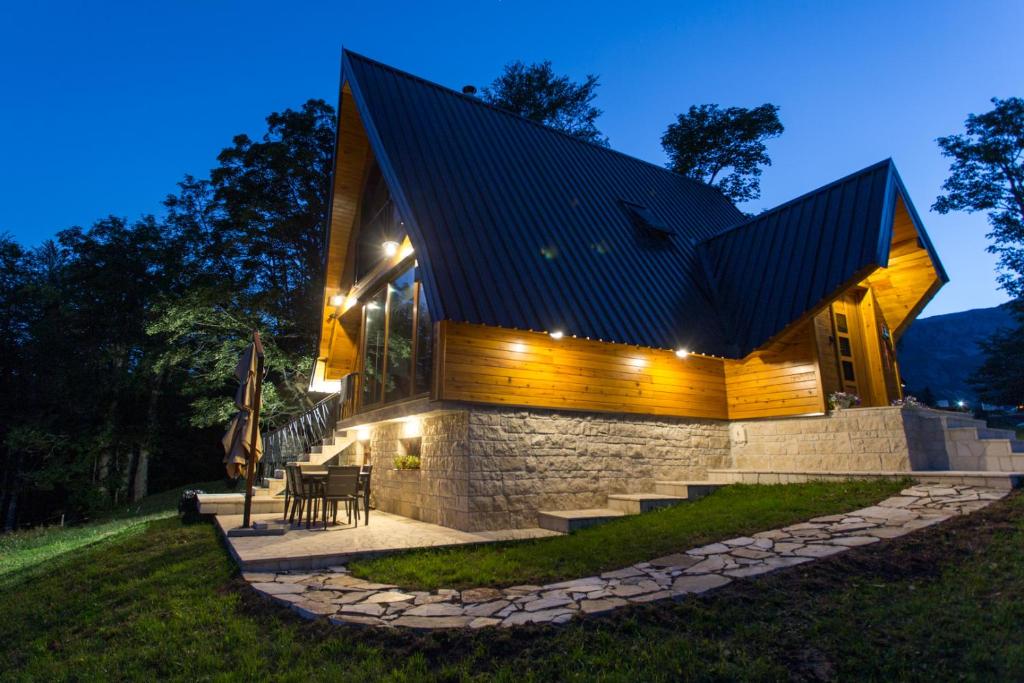una casa con tetto nero e muro di pietra di Vila Sun forest a Žabljak