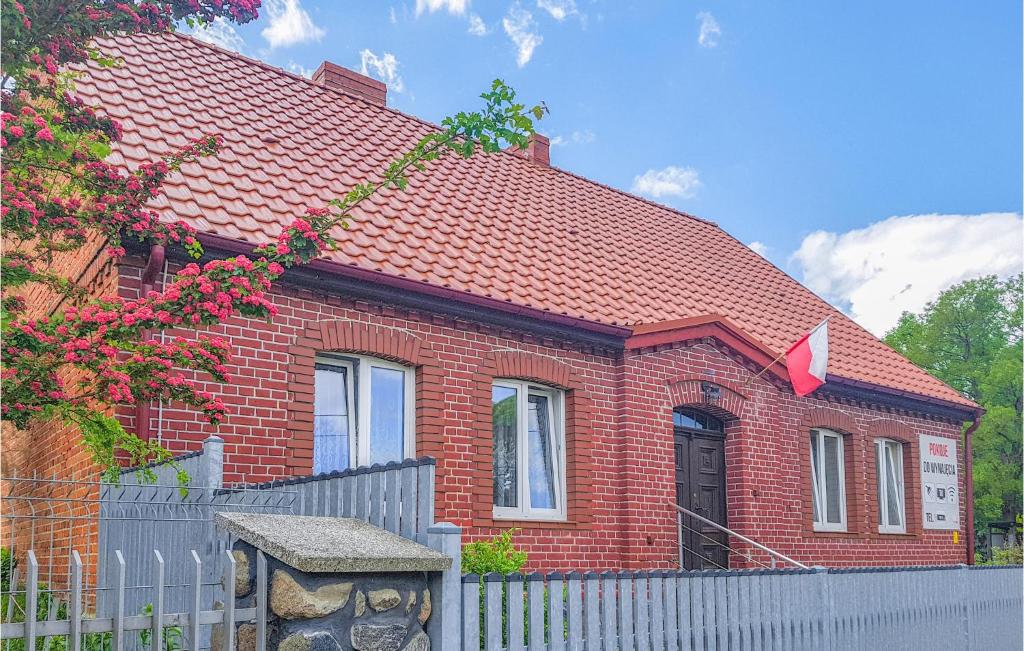 une maison en briques rouges avec une clôture devant elle dans l'établissement Amazing Apartment In Dominikowo With Wifi, à Dominikowo