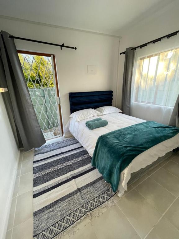 ein Schlafzimmer mit einem Bett und einem großen Fenster in der Unterkunft Cub's Home in Kapstadt