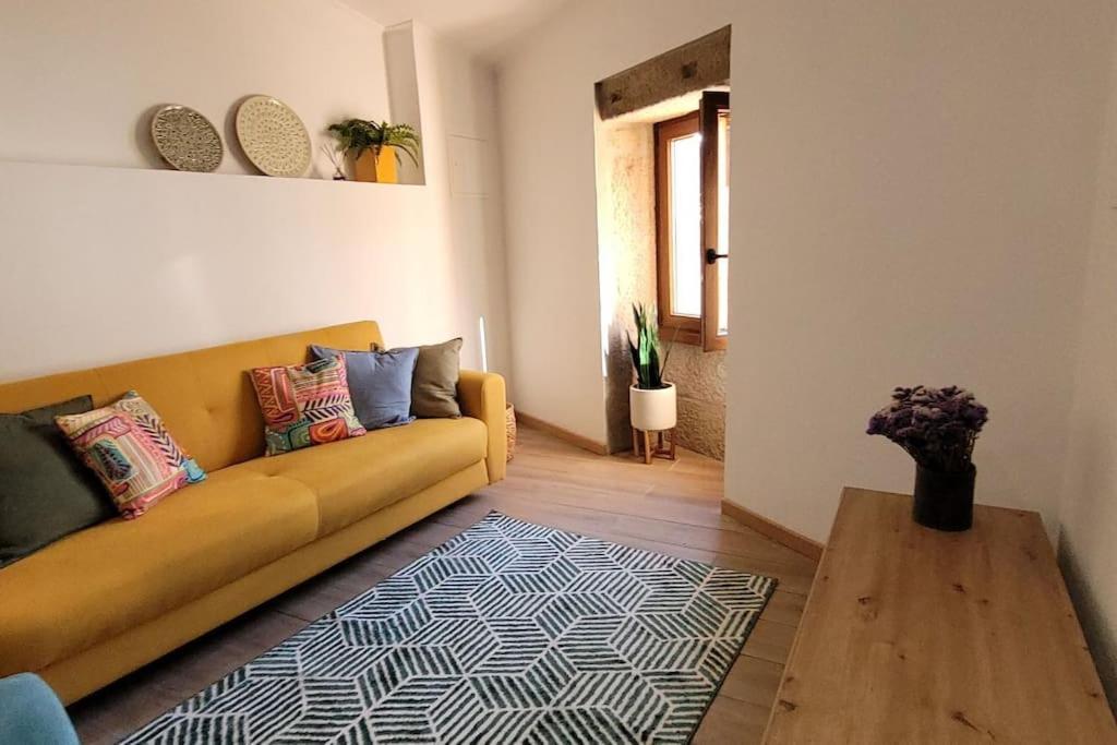 uma sala de estar com um sofá amarelo e uma mesa de madeira em Casa Cereja em Pêro Viseu