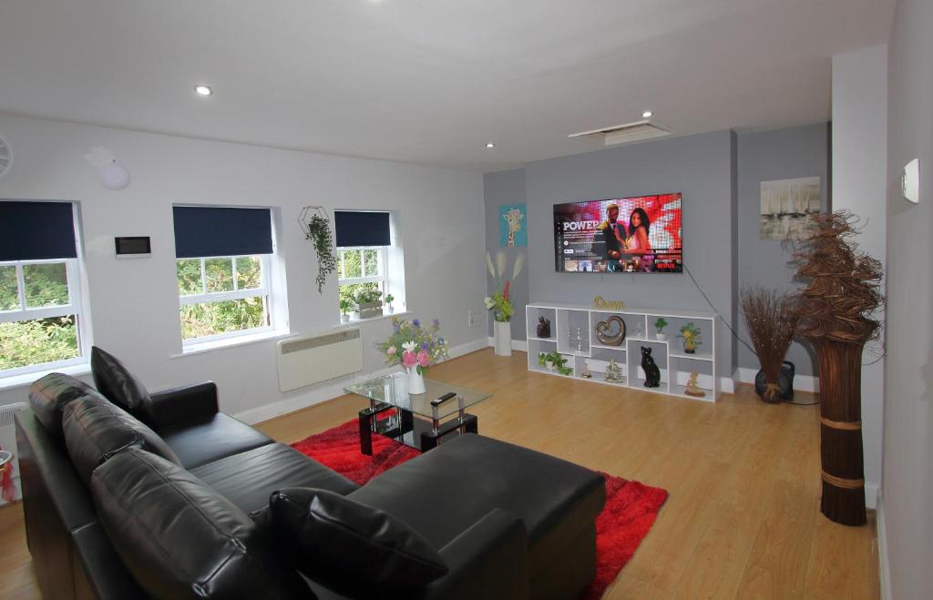 een woonkamer met een zwarte bank en een rood tapijt bij Charming 2 Bed 2 Bath Flat & Parking by CozyNest in Reading