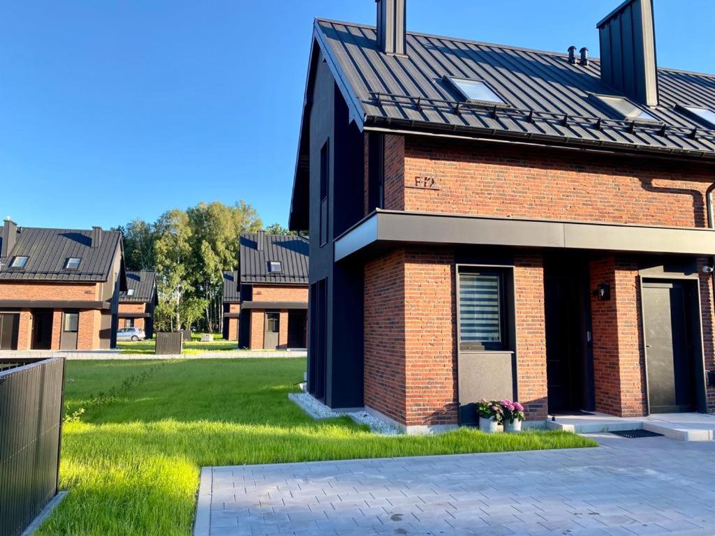 a brick house with a green lawn next to it at White Wave Norda Dębki in Dębki