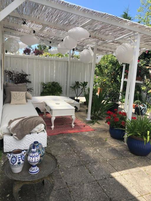 a patio with a bed and a white pergola at MAISON CHATEAU D'OLERON in Le Château-dʼOléron