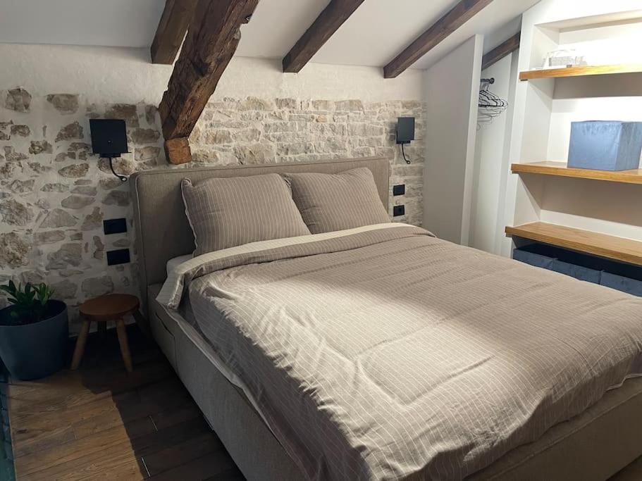 um quarto com uma cama grande numa parede de tijolos em Loft by Villa di Piazza - a home you won’t forget em Visnjan