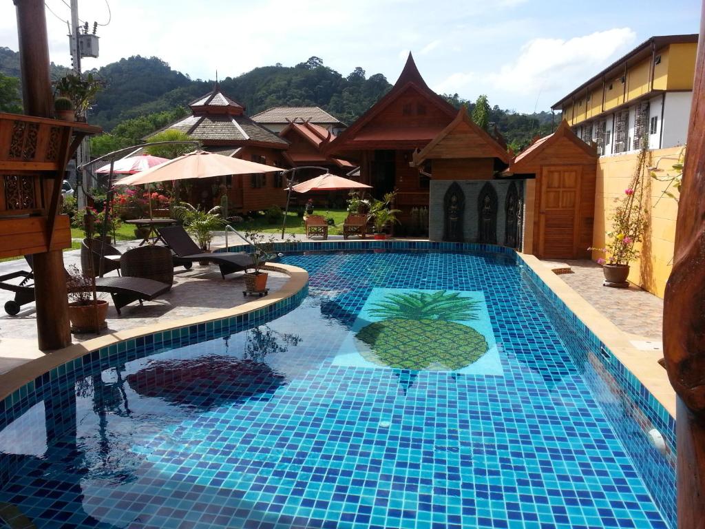 una piscina con azulejos azules en la parte lateral de un edificio en Golden Teak Resort Baan Sapparot, en Kamala Beach