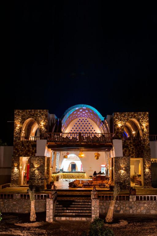 a lit up building with a large building at night at Paradise Sweir in Nuweiba