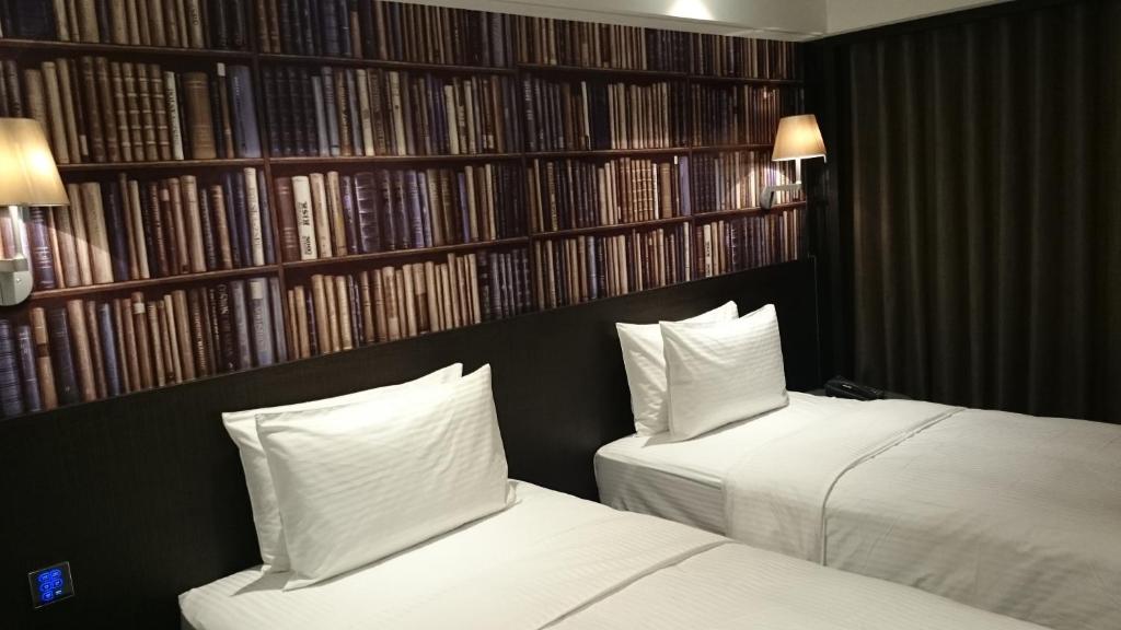 two beds in a hotel room with a book shelf at The Cloud Hotel in Taichung
