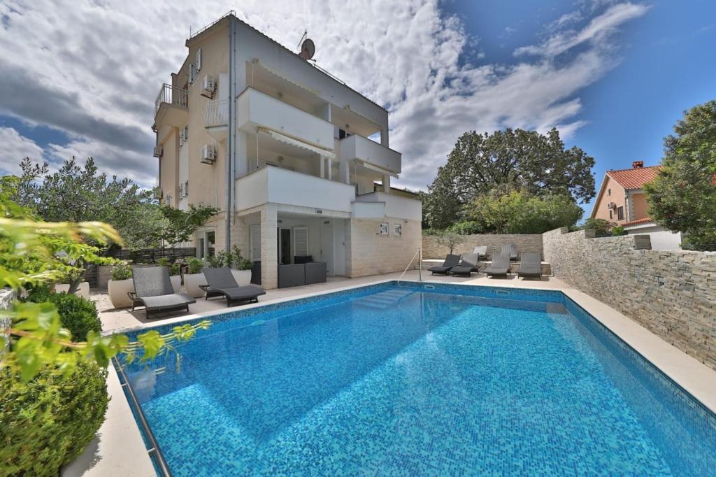 歐克魯東吉的住宿－Seaside apartments with a swimming pool Okrug Donji, Ciovo - 5244，一座别墅,在一座建筑前设有一个游泳池