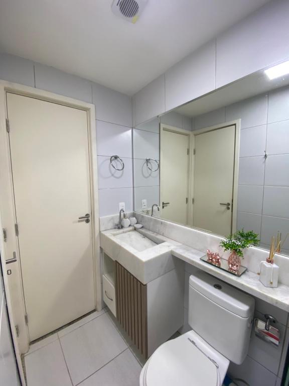 ein Badezimmer mit Toilette, Waschbecken und Spiegel in der Unterkunft Flat Garden 113 Muro Alto Condominio Clube in Porto De Galinhas