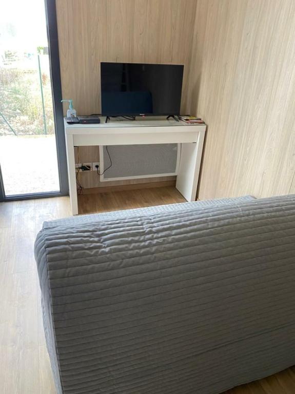 a room with a bed and a desk with a television at Gîte atypique en bois entre ville et verdures in La Chapelle-Saint-Mesmin