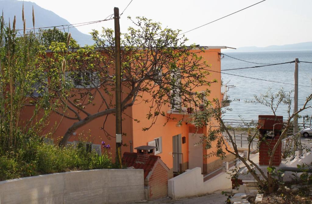 een oranje gebouw met de oceaan op de achtergrond bij Apartments by the sea Duce, Omis - 5275 in Dugi Rat