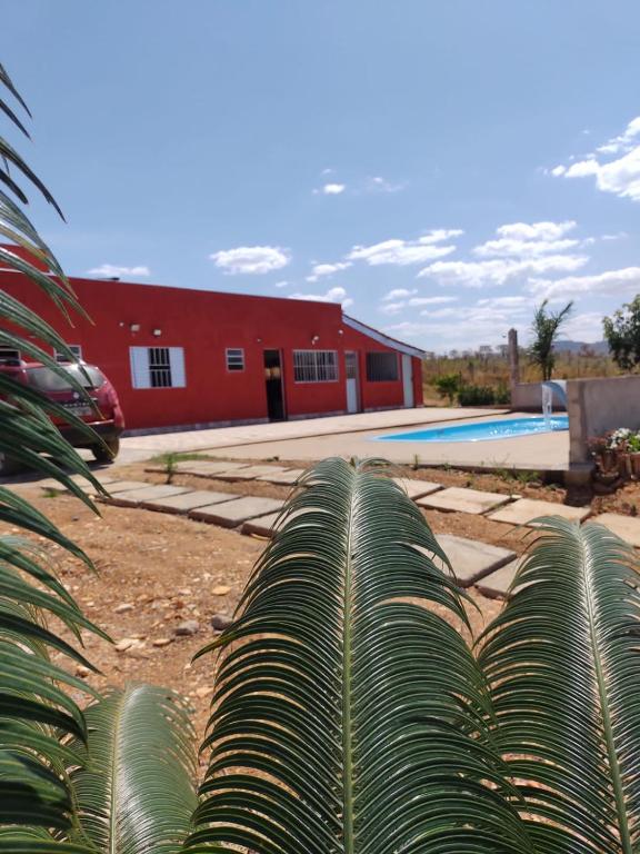 a red building with a pool and a palm tree at POUSADA ALVE VERDe in Capitólio