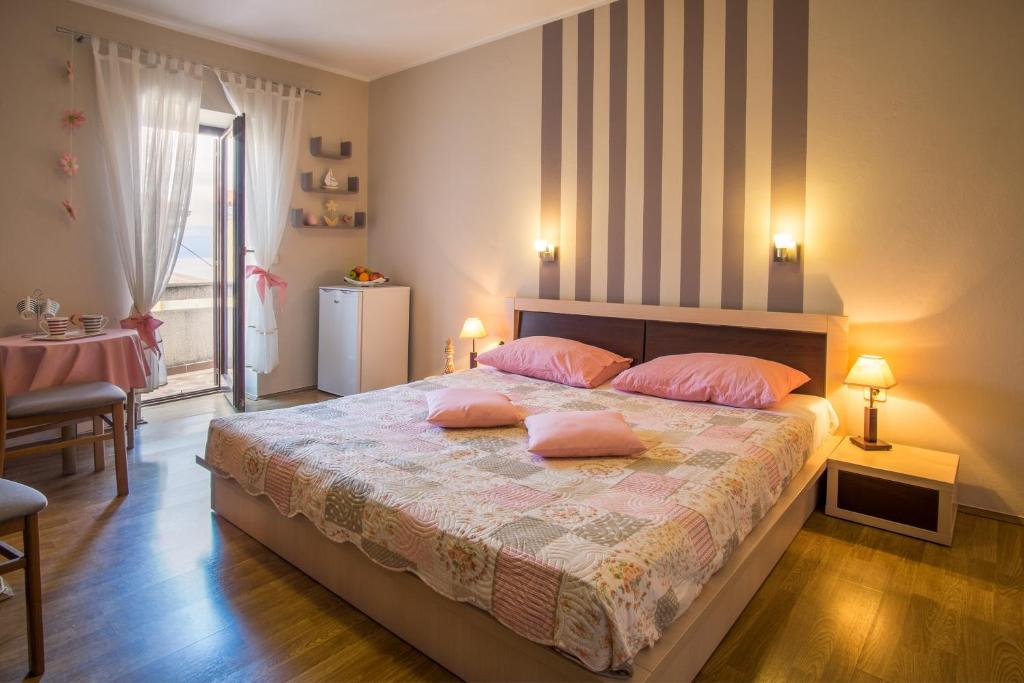a bedroom with a bed with pink pillows on it at Apartments and rooms with parking space Vrbnik, Krk - 5302 in Vrbnik