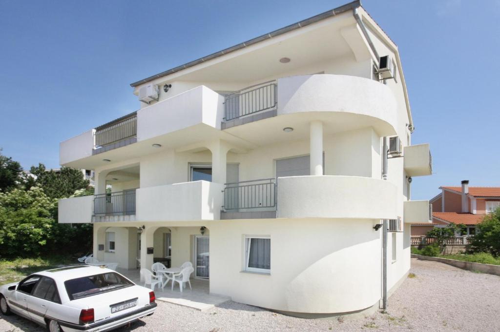 una casa bianca con un'auto parcheggiata davanti di Apartments and rooms with parking space Sveti Vid, Krk - 5323 a Sveti Vid-Miholjice