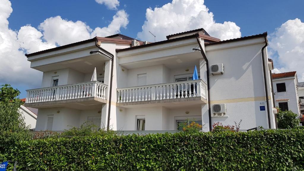 Biały budynek z dwoma balkonami na górze w obiekcie Apartments by the sea Njivice, Krk - 5295 w mieście Nijvice