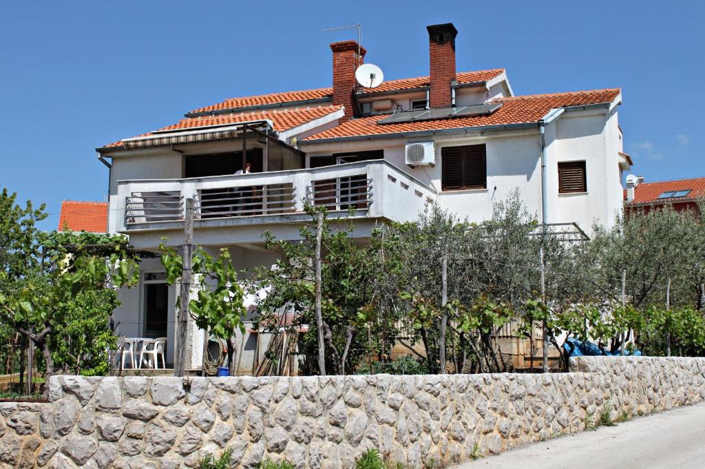 a white house behind a stone wall at Apartment Krk 5294b in Krk