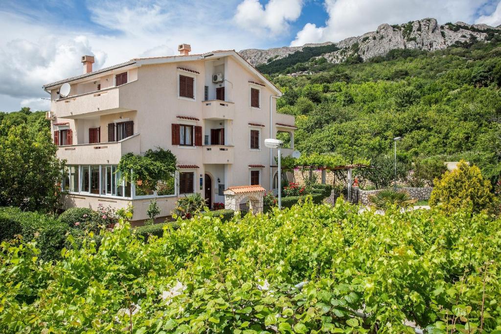 a large house with a mountain in the background at Apartments with a swimming pool Baska, Krk - 5354 in Baška