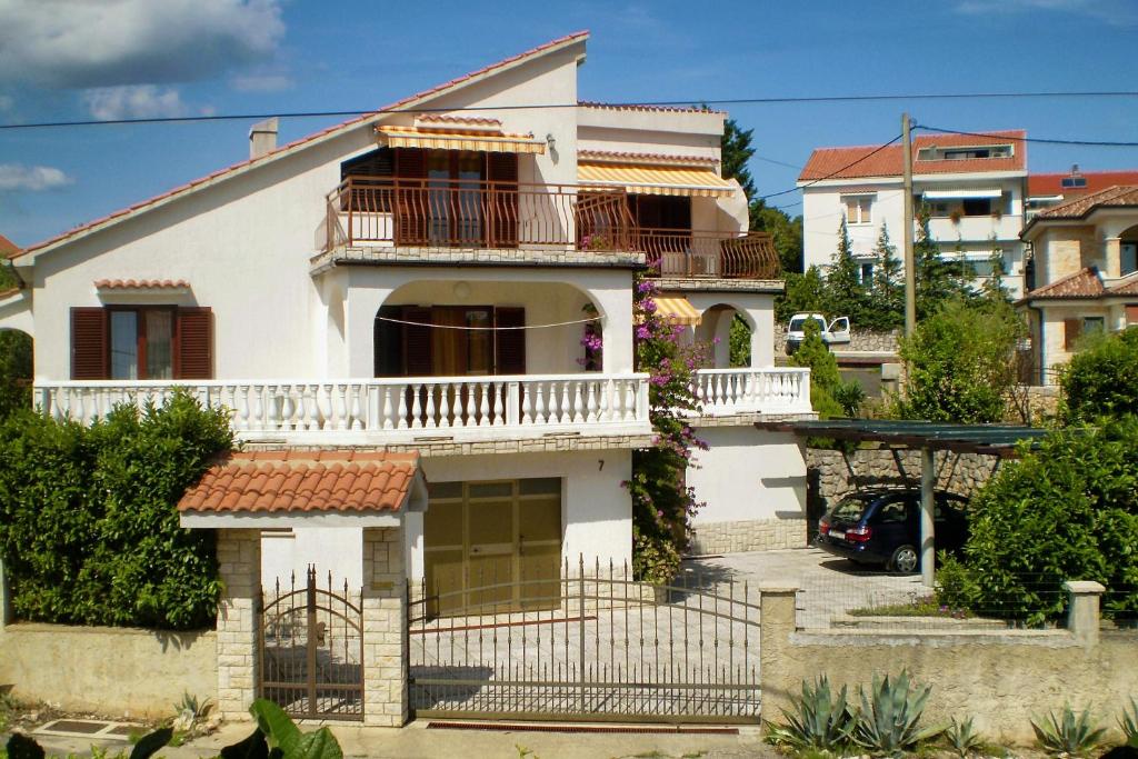 a white house with a balcony and a driveway at Apartments with a parking space Pinezici, Krk - 5319 in Pinezici