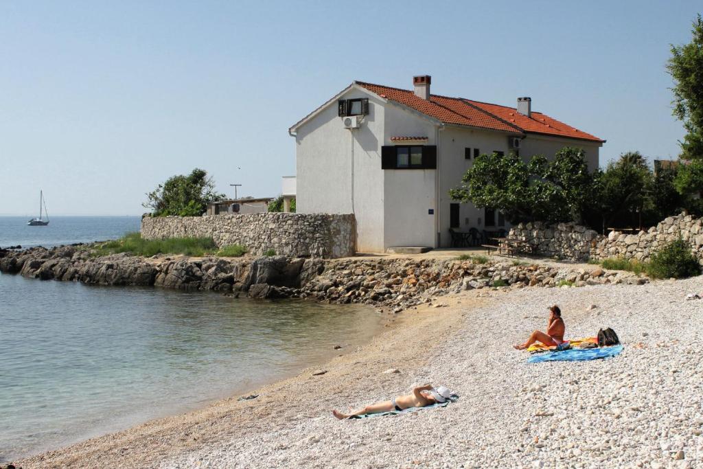 two people laying on a beach next to the water at Apartments by the sea Krk - 5400 in Krk