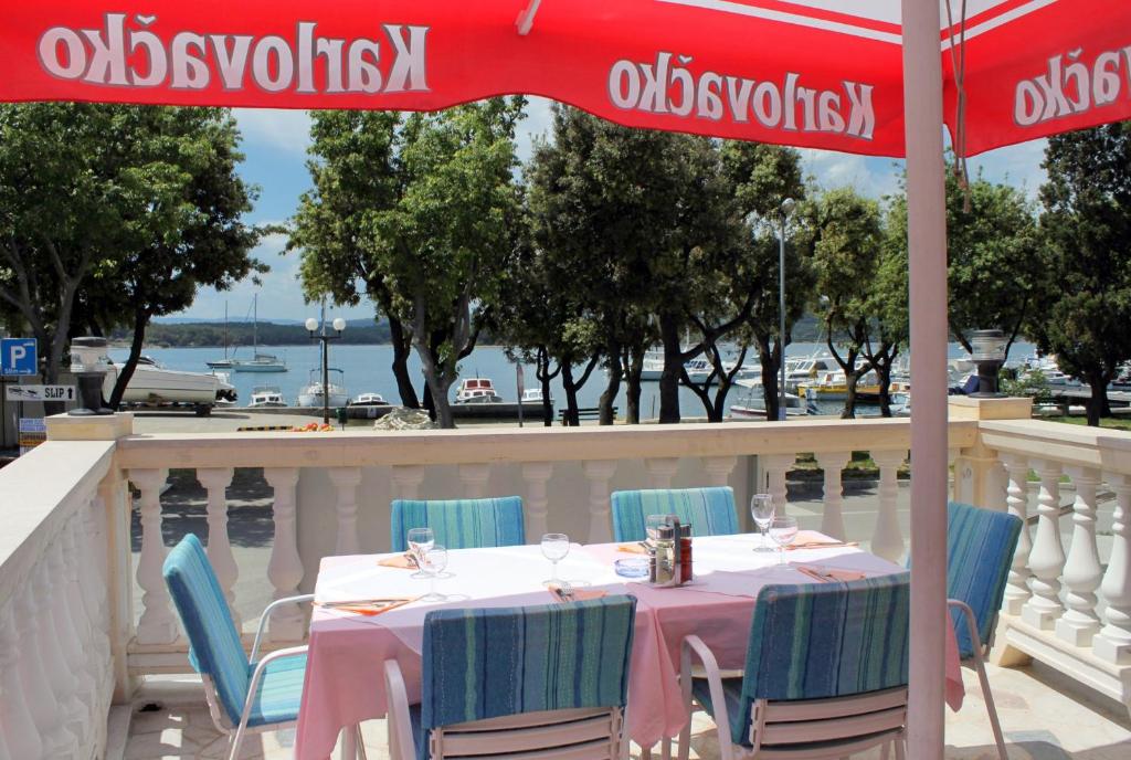 a table with chairs and an umbrella on a balcony at Apartments by the sea Punat, Krk - 5328 in Punat