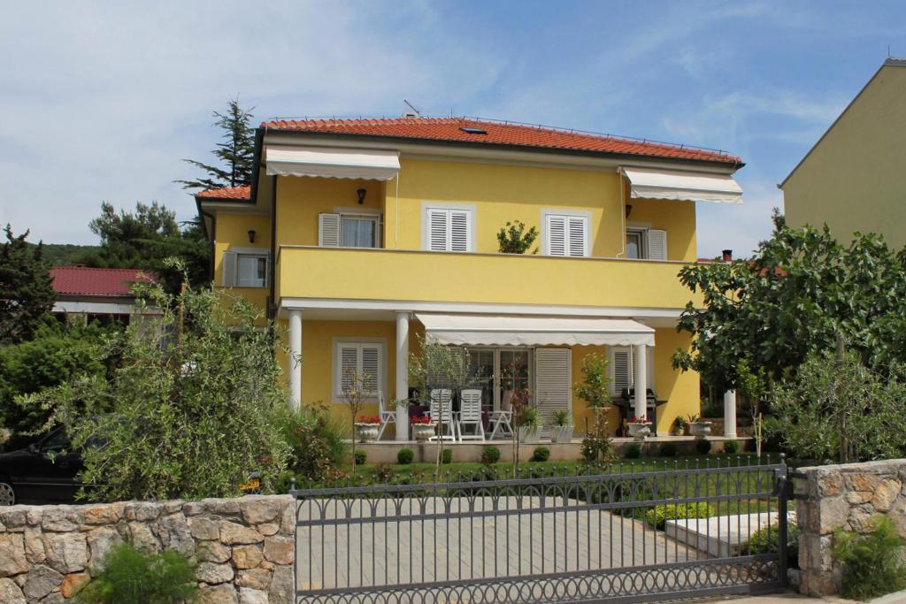 a yellow house with a fence in front of it at Apartment Punat 5408a in Punat
