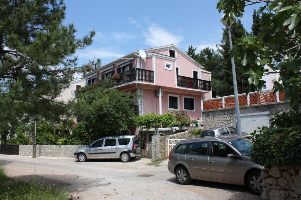 dos autos estacionados frente a una casa rosa en Apartments and rooms with parking space Punat, Krk - 5363 en Punat